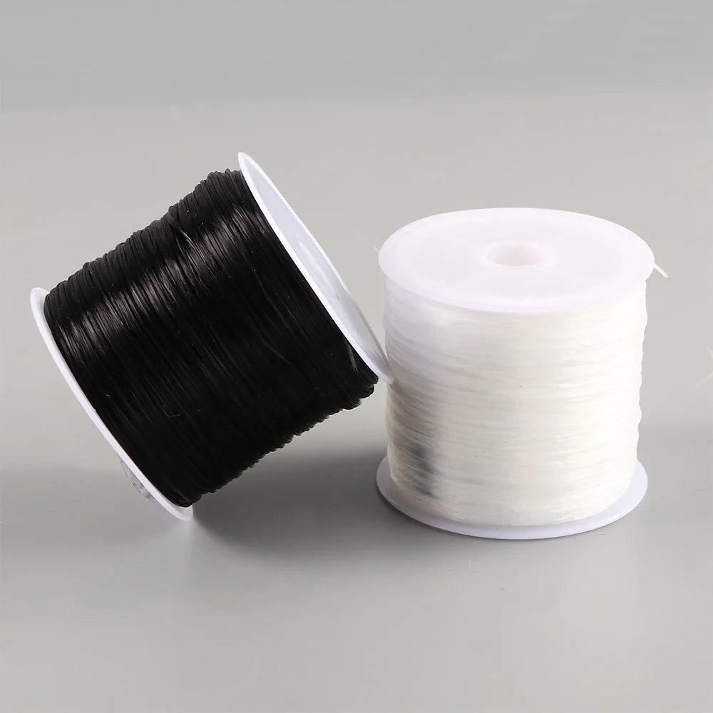 A spool of black flat elastic beading thread next to a roll of white flat elastic beading thread.