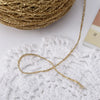 A spool of metallic gold silk yarn is shown next to a finished piece of lacy gold crochet work.