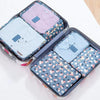 A set of six fabric storage organizers in various shades of pink and blue for clothes.