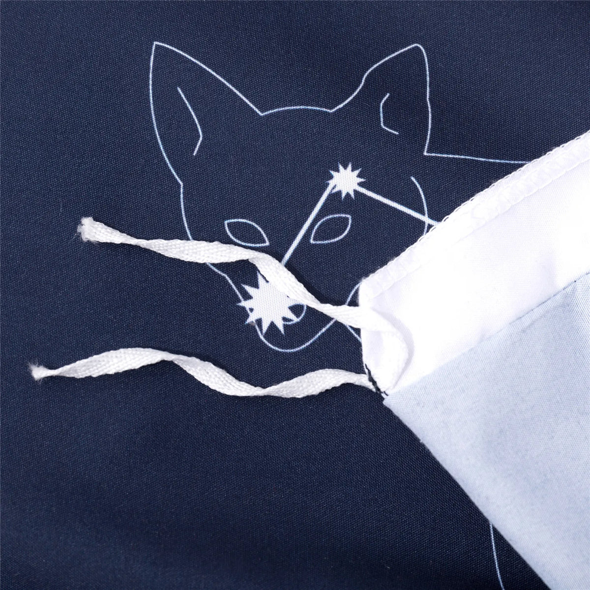 A dark blue fabric features a white outline of a fox head with stars, tied by a white string.