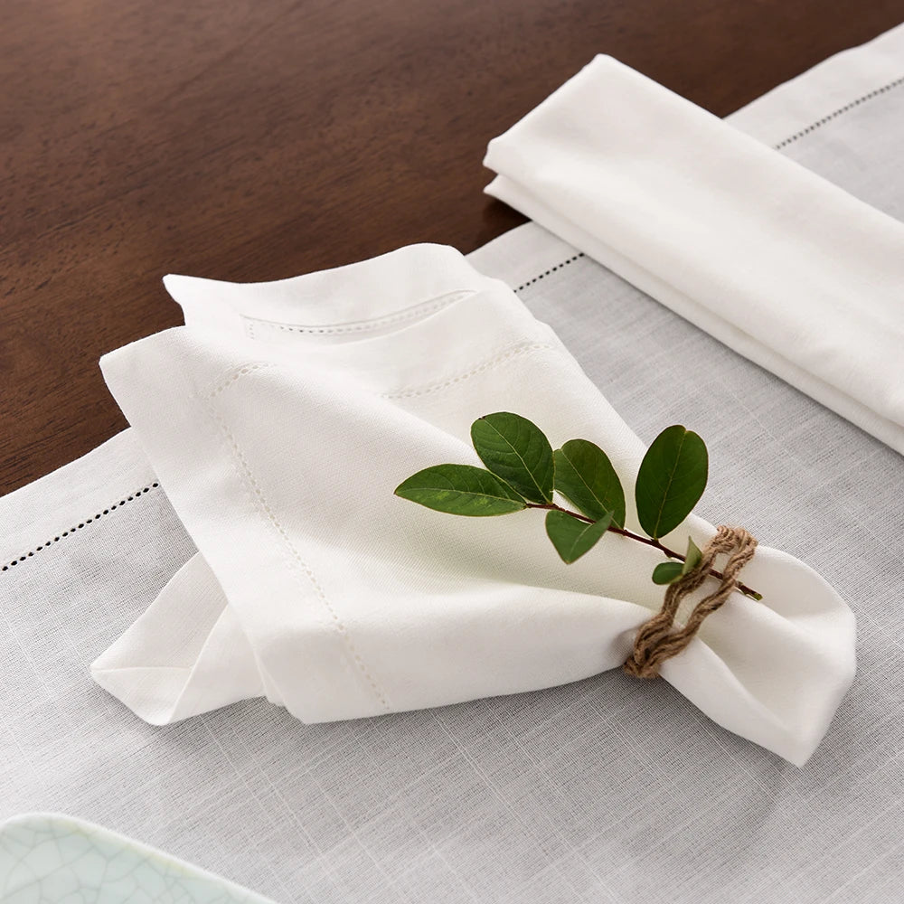 A stack of white linen napkins tied with twine rests on a light gray cloth.