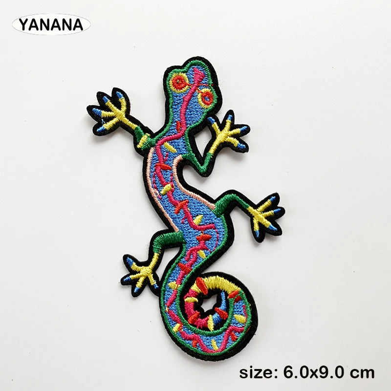 An embroidered patch of a lizard with vibrant blue, yellow, and red markings on a black background.