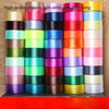A vertical display of colorful satin ribbon rolls in various shades and lengths for gift wrapping and crafts.