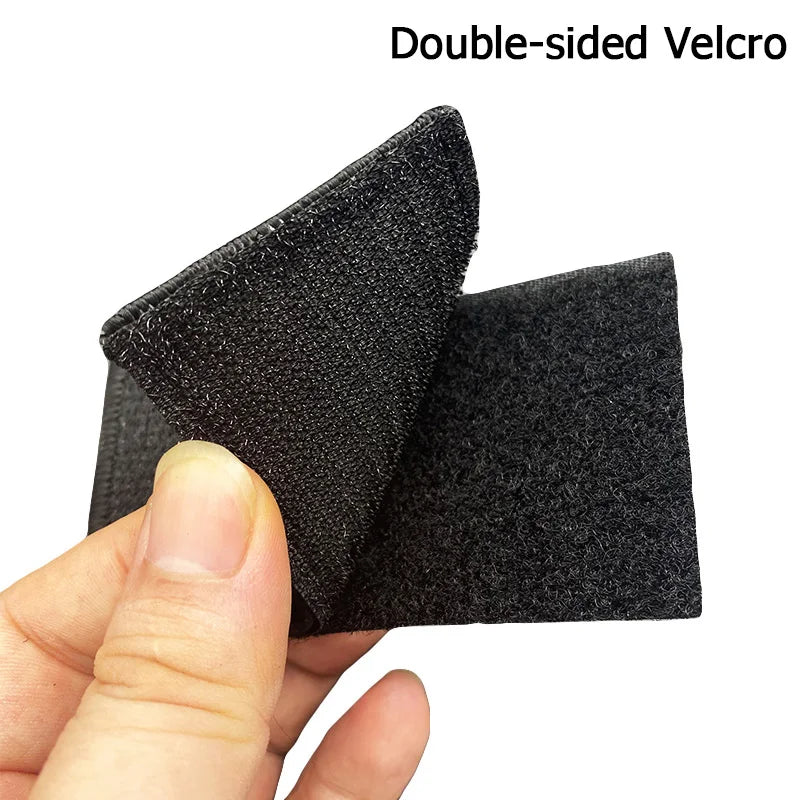 A hand holds a double-sided Velcro patch for tactical gear, showing the black fabric texture.