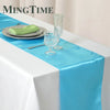 Elegant satin blue table runner with a green napkin and glassware on a white tablecloth
