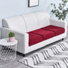 A white sofa with a red seat cushion cover and a white patterned rug.
