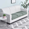 A white sofa features a green stretchable fleece seat cushion cover on a light gray rug.