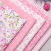 Pink floral and stripe cotton twill fabric rolls with pink yarn pom-poms