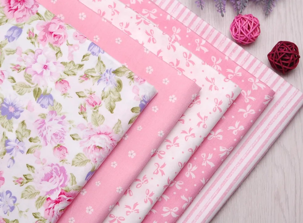 Pink floral and stripe cotton twill fabric rolls with pink yarn pom-poms