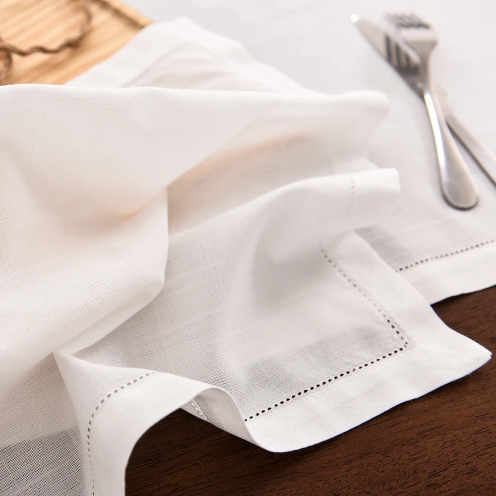 White linen table linens and napkins draped on a wooden surface.