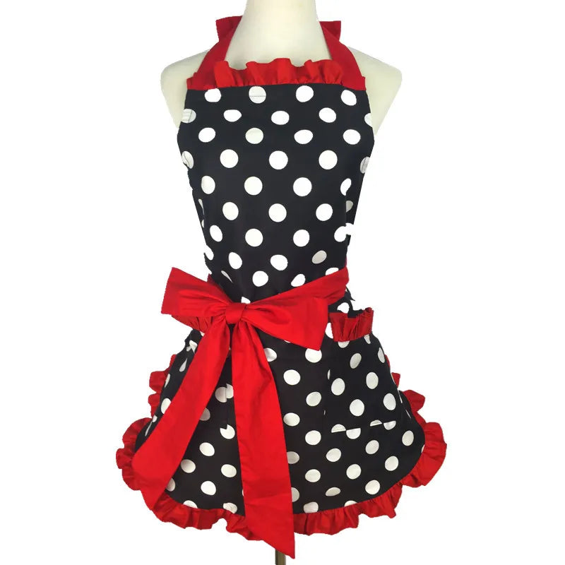 A black polka dot ruffle apron with red ribbon and pockets displayed on a mannequin.