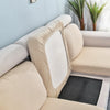 A beige stretch sofa seat cushion protector slipcover is shown on a light blue wall with potted greenery.