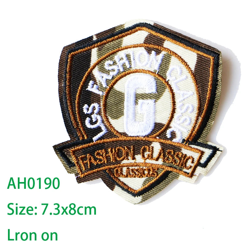 An embroidered iron-on patch featuring the text Fashion Classic and a letter G on a dark olive background.