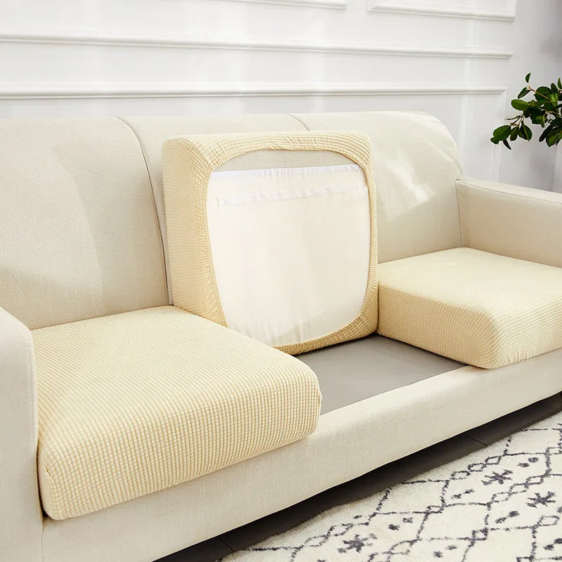 A beige stretchable fleece seat cushion cover is shown on a light-colored sofa with a gray cushion.