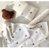 White coral fleece flannel blanket with brown bear appliqués folded and draped
