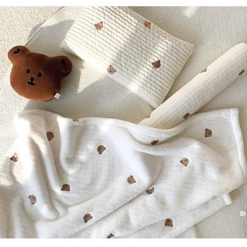 White coral fleece flannel blanket with brown bear appliqués folded and draped