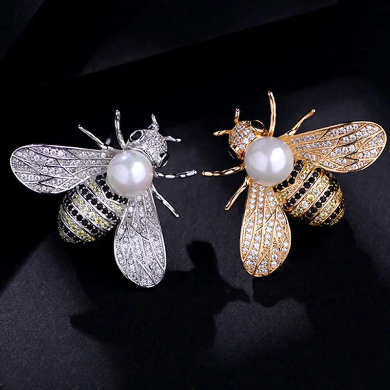 A pair of crystal bee brooches featuring gold-toned wings, black and gold detailing, and white pearls.