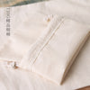 A close-up of a natural cotton drawstring gift bag in beige fabric resting on a light background.