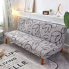 Gray geometric print spandex slipcovers on a sofa bed with a white mantelpiece in a bright room.