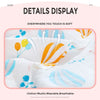 A white cotton muslin swaddle blanket with orange and blue floral designs is shown being touched.