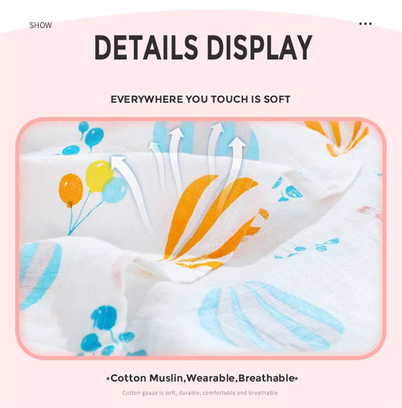A white cotton muslin swaddle blanket with orange and blue floral designs is shown being touched.