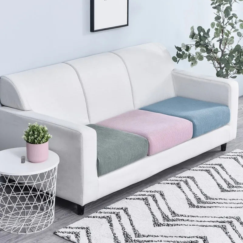A white sofa is adorned with colorful fleece seat cushion covers in shades of blue, pink, and green.