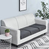 A modern light gray sofa with a dark gray seat cushion cover placed in a bright living room.