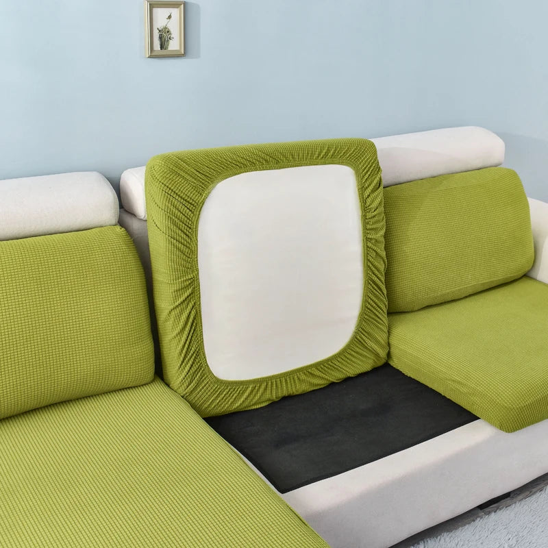 A lime green stretch sofa seat cushion protector slipcover with a white interior and black pad.