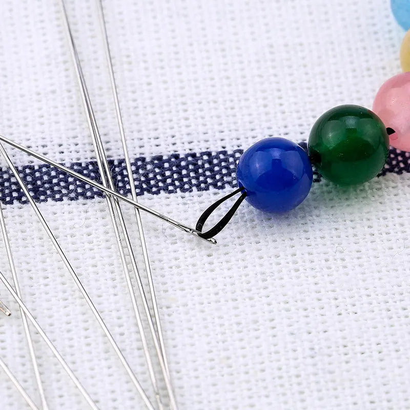Precision stainless steel beading needles with colorful beads on a white background