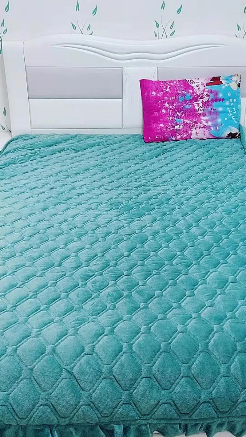 A teal quilted bedspread with a diamond pattern is displayed on a white bed with a headboard and a bright pink decorative pil