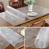 Clear PVC tablecloth with floral pattern placed on a wooden table.