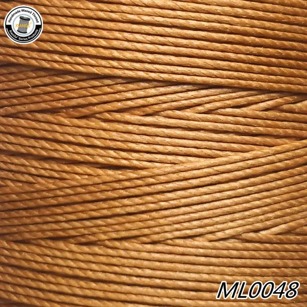A close-up view of a spool of golden brown wax thread embroidery cord.