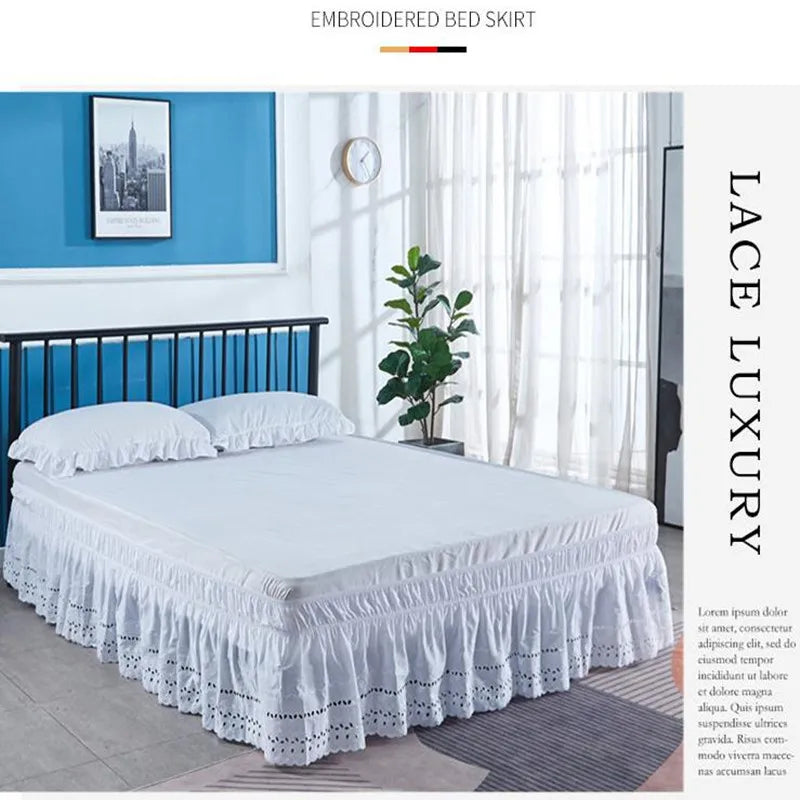 White embroidered ruffle bed skirt displayed on a bed in a bright bedroom setting.