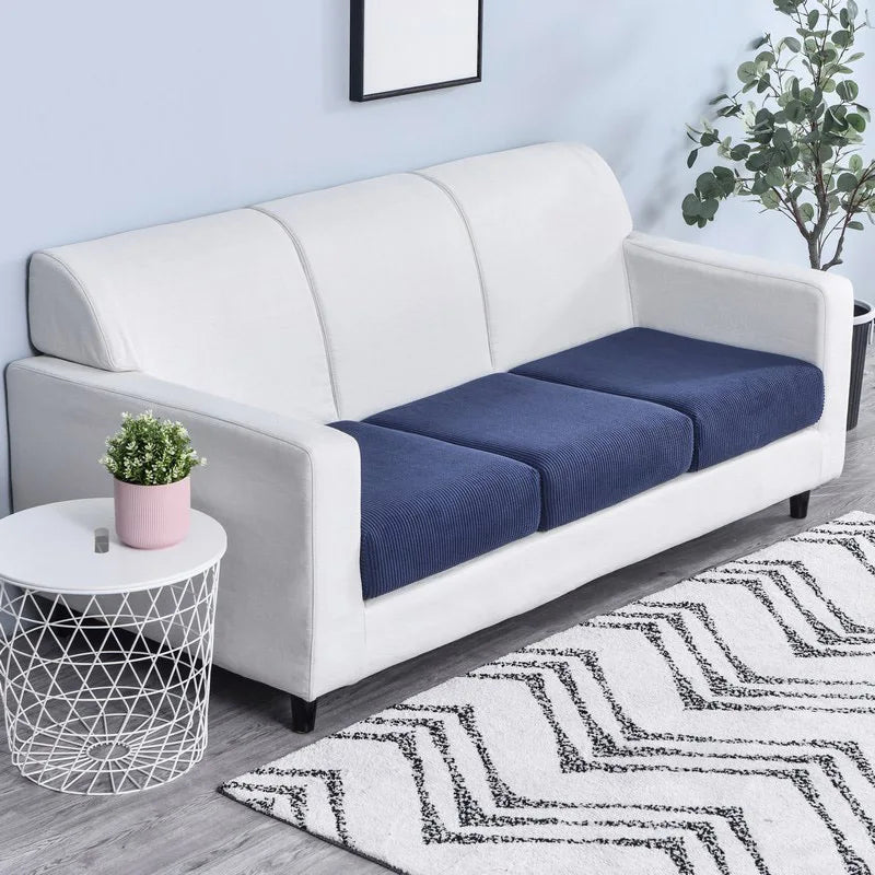 A white sofa with a dark blue seat cushion cover placed on a light rug.