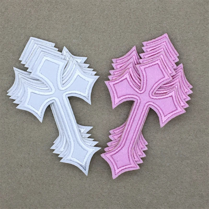 Two embroidered cross applique patches, one white and one pink, displayed on a neutral background.