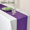 Elegant purple satin table runner displayed on a white tablecloth with silverware and glassware.