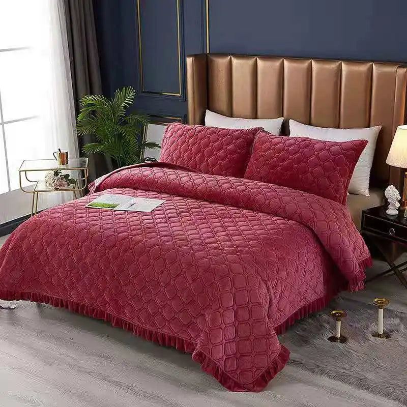 A deep red quilted velvet bedspread with a diamond pattern displayed on a bed.