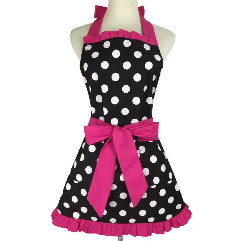 A black polka dot ruffle apron with pink ribbon ties displayed on a mannequin.