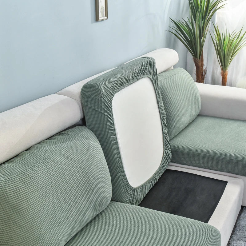 A light green stretch sofa seat cushion protector slipcover on a white sofa.