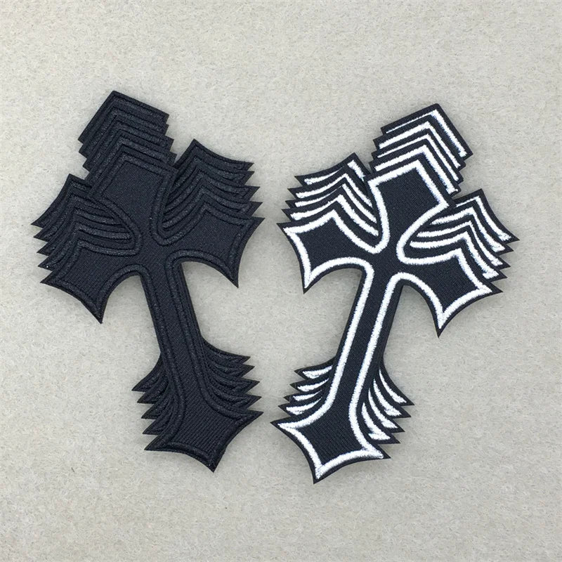 Two embroidered cross applique patches, one black and one white, displayed on a light gray background.