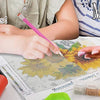 Hands are working on a puzzle or craft project with embroidery thread and fabric on a table.