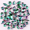 A collection of green and iridescent silver claw rhinestones scattered on a white background.