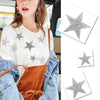 A woman wearing a white top and denim jacket holds several silver glitter rhinestone star patches.
