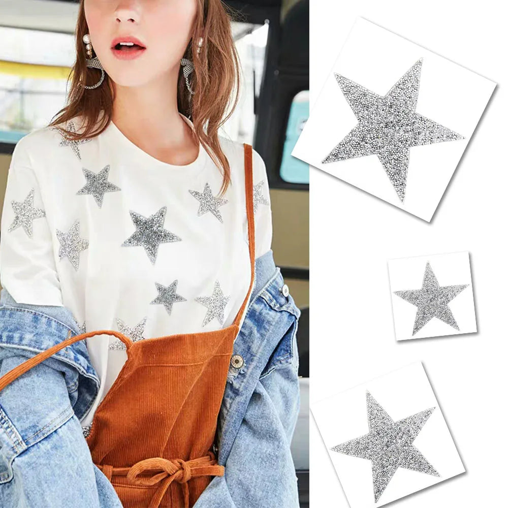 A woman wearing a white top and denim jacket holds several silver glitter rhinestone star patches.