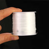 A hand holds a spool of white flat elastic beading thread for jewelry making.