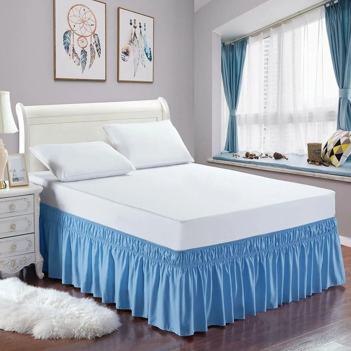 A white bed with a blue ruffle skirt and bedding in a bedroom setting.