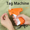 A hand holds an orange and white tag machine with a white tag being applied to fabric.
