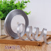 Roll of silver satin ribbon with a white core displayed on a wooden surface.