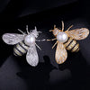 A pair of crystal bee brooches featuring gold-toned wings, black and gold detailing, and white pearls.