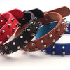 A collection of leather wristbands in various colors, including red, black, brown, and blue, featuring studs and spikes.